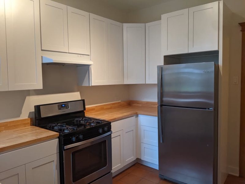 White shaker cabinets with butcher block countertops and stainless range