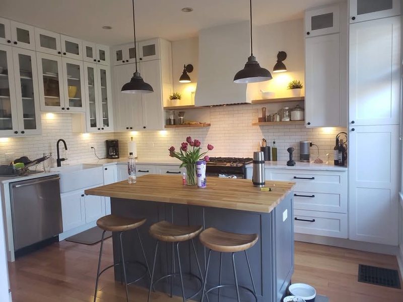 White shaker kitchen with subway tile, open shelves, farmhouse sink and butcher block island