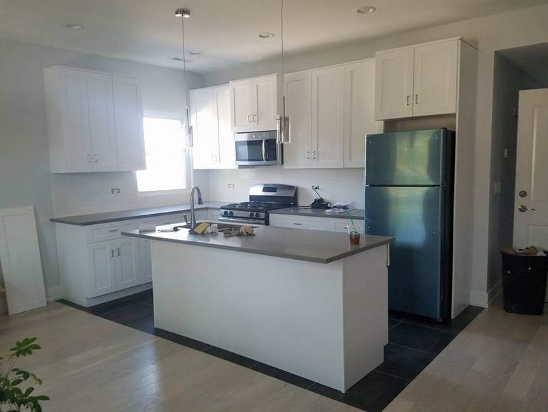 White shaker kitchen with gray countertops, island and stainless appliances